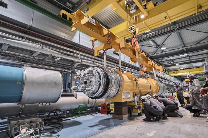 yellow cylindrical magnet being manoeuvred with a crane next to a teal one